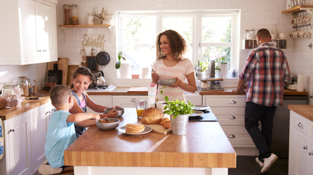 Family At Home Eating Breakfast In Kitchen Together