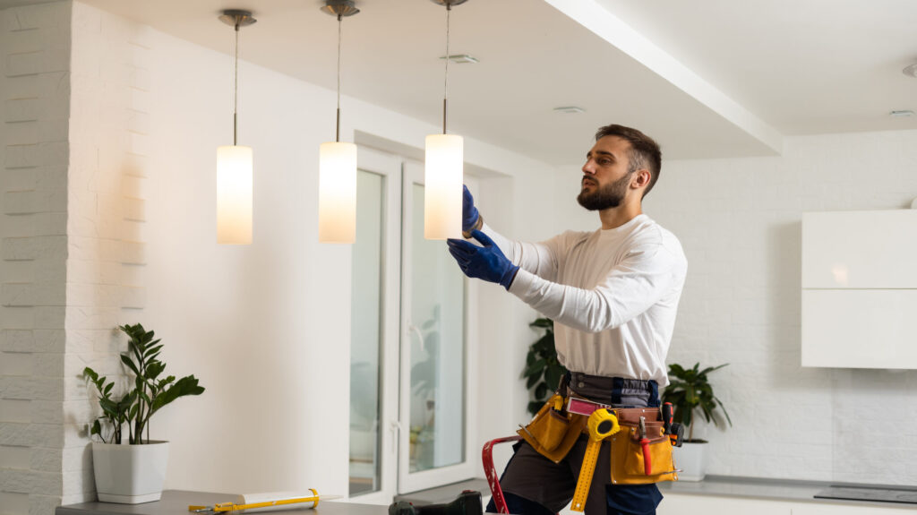 Electrician installs lamp lighting and spot loft style on ceiling