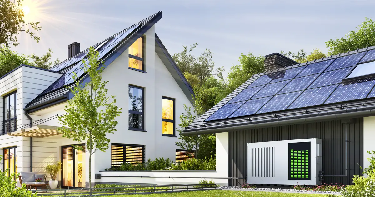 A modern, energy-efficient home with solar panels on the roof and a battery storage system installed outside. The house is surrounded by lush greenery, emphasizing sustainability and renewable energy solutions.
